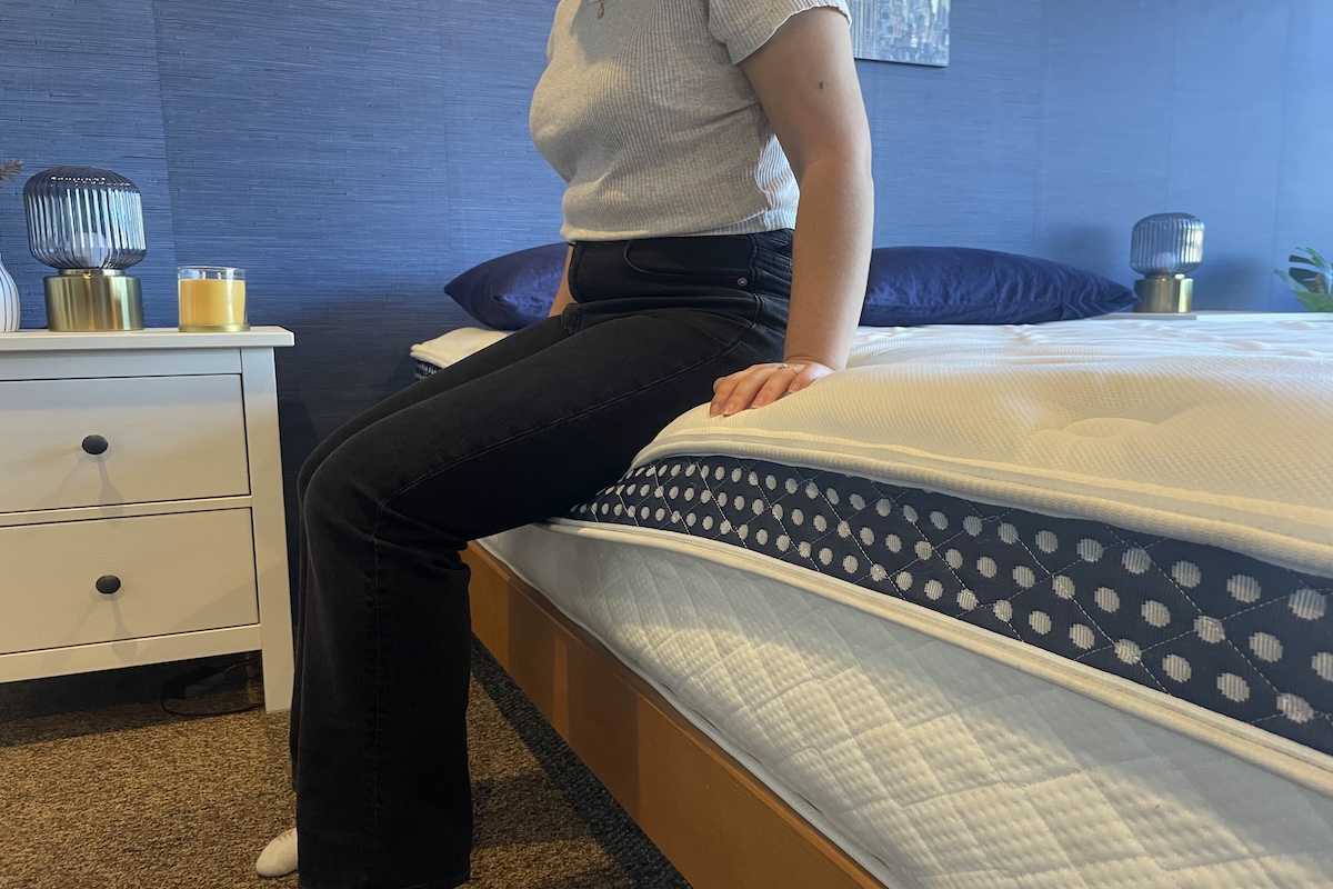 A woman sits on the edge of The WinkBed. 